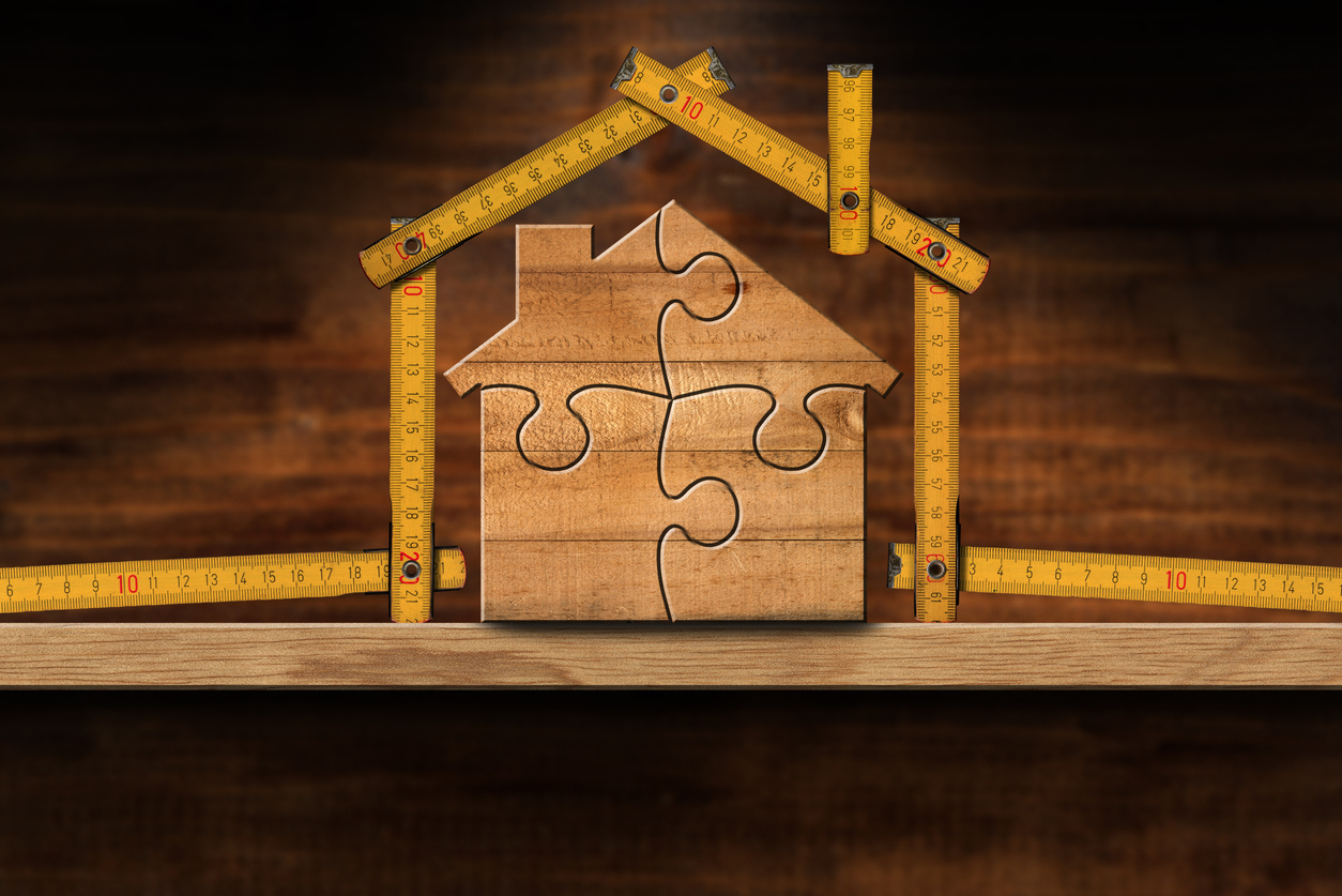Small house model made from measuring tools and puzzle pieces